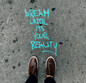 realizzare un sogno. piedi su asfalto con scritta dream until ius your reality