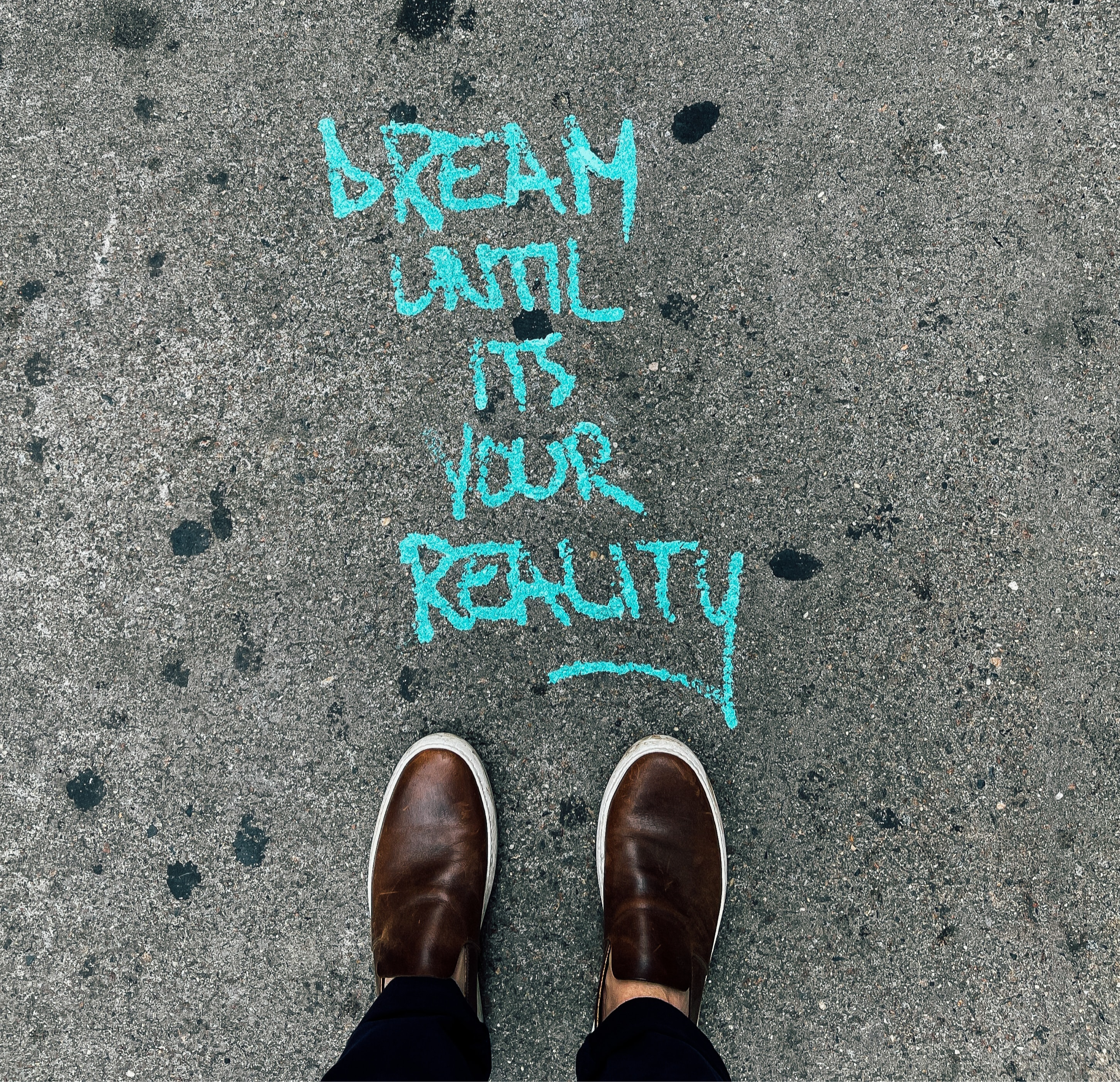 realizzare un sogno. piedi su asfalto con scritta dream until ius your reality